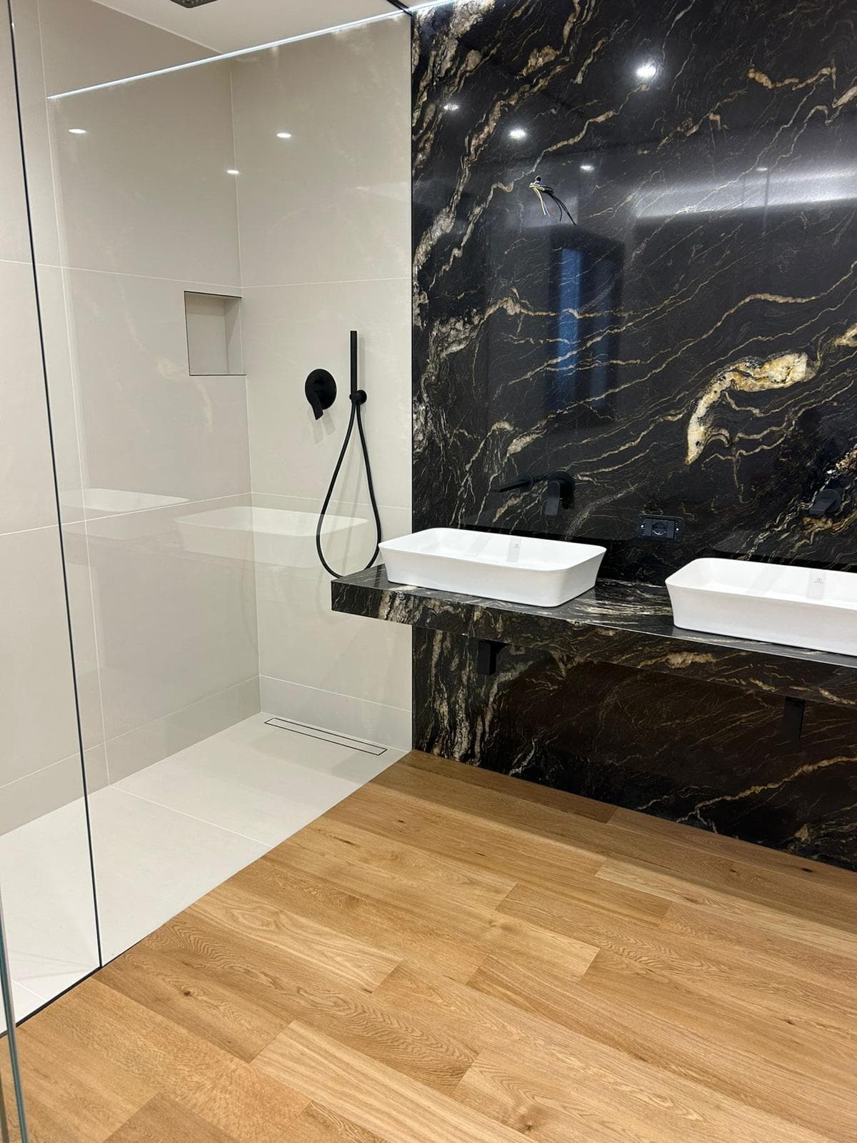 Bagno con rivestimento in marmo nero e doppio lavabo