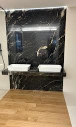 Bagno con parete e lavabi in marmo nero